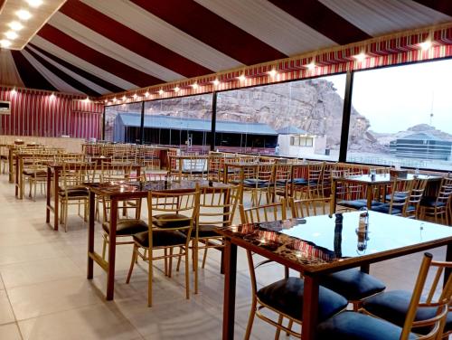 a restaurant with tables and chairs and a large window at Harir Rum luxury camp in Wadi Rum