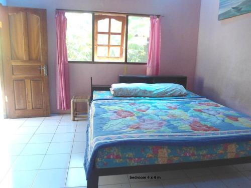 ein Schlafzimmer mit einem Bett mit einer bunten Decke und einem Fenster in der Unterkunft Bali Traditional homestay in Gianyar