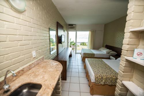 a hotel room with two beds and a sink at Portogalo Suite Hotel in Angra dos Reis