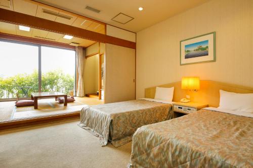 a hotel room with two beds and a large window at Amanohashidateso in Miyazu