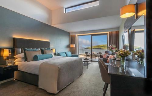 a bedroom with a large bed and a living room at Dingle Skellig Hotel in Dingle