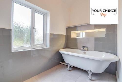 a white bath tub in a bathroom with a window at Lovely detached Cottage, Flint in Flint