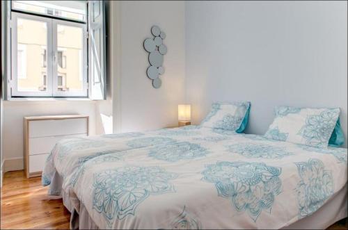 um quarto com uma cama com lençóis azuis e brancos e uma janela em Zaire Retreat Apartment em Lisboa
