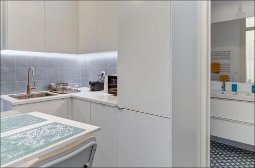 uma cozinha branca com armários brancos e um lavatório em Zaire Retreat Apartment em Lisboa