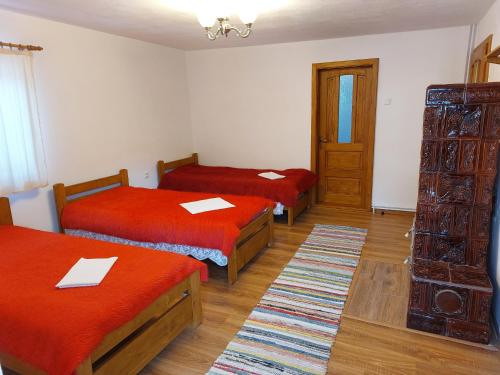 una camera con tre letti con lenzuola rosse di Tulipános Vendégház 
