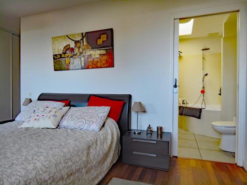 um quarto com uma cama e uma casa de banho com um lavatório em L'OASIS - Loft standing - Terrasse Rooftop - Jacuzzi Spa - Parking em Baiona