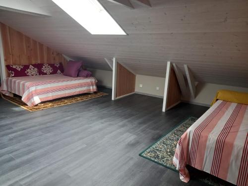 une chambre mansardée avec deux lits et une lucarne dans l'établissement La Remise de SoSo, à Chambon-le-Château