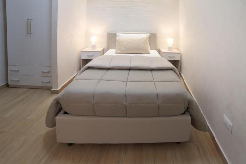 a large bed in a white room with two night stands at GREEN - Bed and Breakfast a Castrovillari in Castrovillari