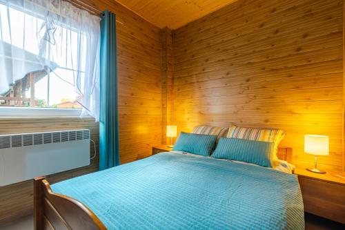 a bedroom with a bed with a wooden wall at Domki nad morzem Ośrodek Baltica, Wicie in Wicie