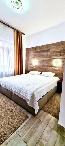 a bedroom with a large bed with a wooden wall at Pensiunea Ioana in Sadova