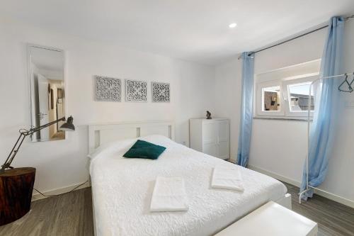 een slaapkamer met een wit bed en een groen kussen bij Zen Village Verde in Fernao Ferro
