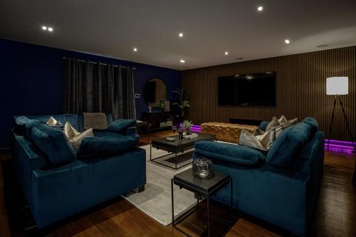 a living room with blue couches and a tv at Spengarth House by STAMP SA in Blackpool