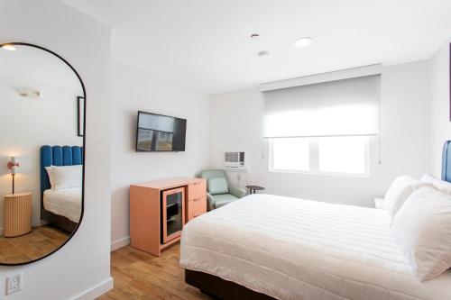 a white bedroom with a bed and a mirror at Grove Hotel in Cherry Grove