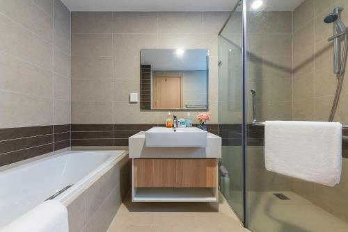 a bathroom with a tub and a sink and a shower at YO's Homes Rivergate Apartment Infinity Pool Near District 1 in Ho Chi Minh City