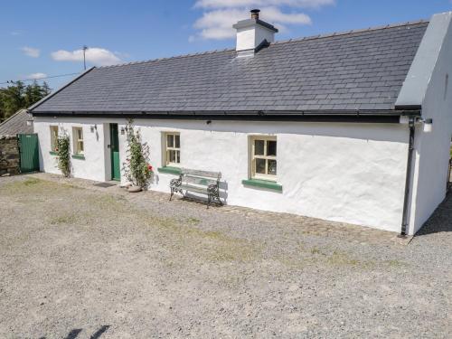 a white cottage with a bench in front of it at Old Mike's Cottage in Westport