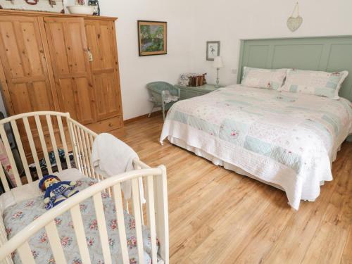 a bedroom with a bed and two cribs at Old Mike's Cottage in Westport