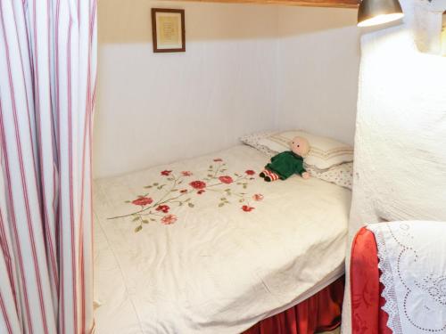 a small bed in a room with a doll on it at Old Mike's Cottage in Westport