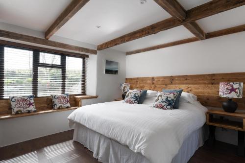 a bedroom with a white bed and two windows at The Rum House in Helston