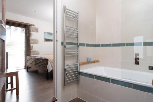 a bathroom with a bath tub and a bed at The Rum House in Helston