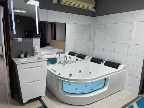 a bathroom with a bath tub and a sink at Family White Hotel in Gjilan