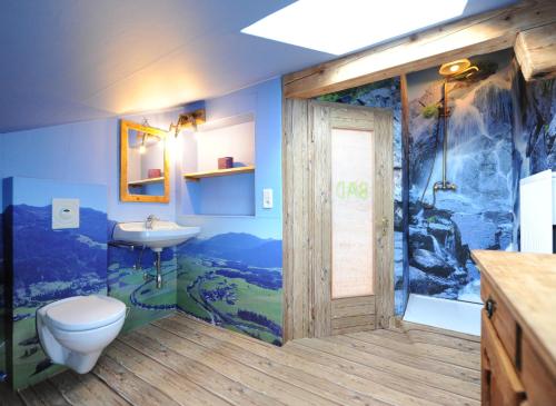 a bathroom with a toilet and a sink with a mural at Appartment Eggerhof in Saalfelden am Steinernen Meer