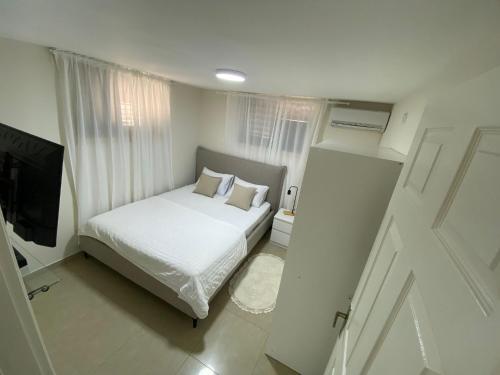 um quarto branco com uma cama e uma televisão em יחידת קורל בלב הגליל העליון coral unit em Quriate-Chemoná