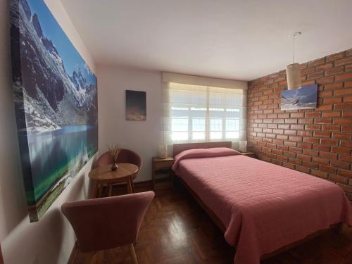 1 dormitorio con cama roja y pared de ladrillo en Amelita Hotel Boutique, en Huaraz