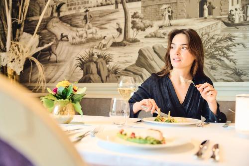 une femme assise à une table mangeant de la nourriture dans l'établissement Grand Hotel du Lac - Relais & Châteaux, à Vevey