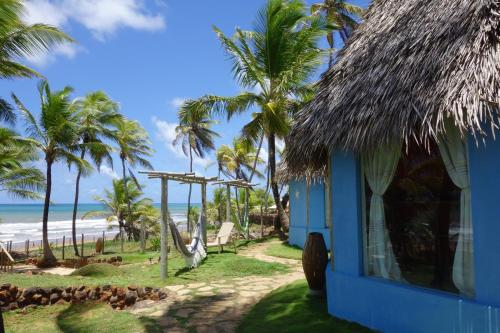 a blue house on the beach with palm trees at Pousada Capitù in Imbassai
