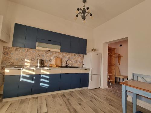 a kitchen with blue cabinets and a white refrigerator at Pokoje Apartament LUX in Mikołajki