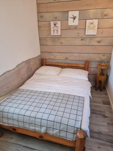 a bed in a room with a wooden wall at Pokoje Apartament LUX in Mikołajki