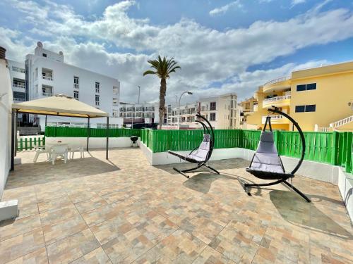 eine Terrasse mit 2 Stühlen und einem grünen Zaun in der Unterkunft Relax Beach House in Puerto de Santiago