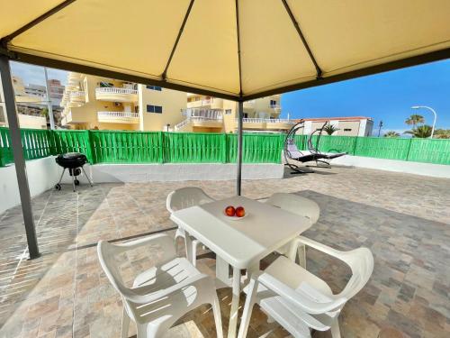 ein weißer Tisch und Stühle unter einem gelben Sonnenschirm in der Unterkunft Relax Beach House in Puerto de Santiago