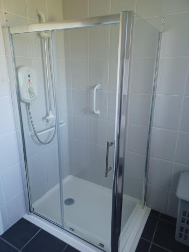 La salle de bains est pourvue d'une douche avec une porte en verre. dans l'établissement Hill view Cottage, à Curr