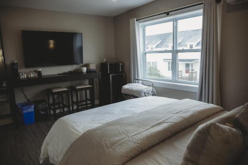 1 dormitorio con 1 cama, TV y ventana en Riverside Suites en Grand Falls -Windsor