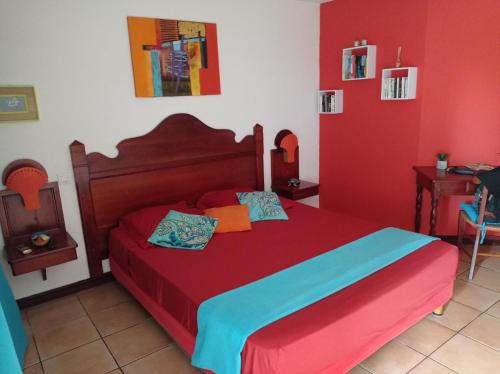 a bedroom with a bed with red and blue sheets at Studio Mahogany in Sainte-Anne