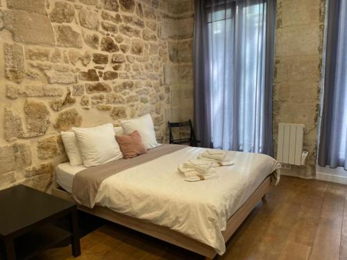 a bedroom with a large bed with a stone wall at Maison le Bac Paris Aparthotel in Paris