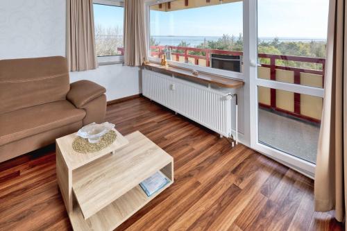 a living room with a couch and a large window at Terrassenhaus, FeWo 88 in Duhnen