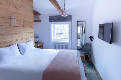 a bedroom with a bed and a tv on a wall at Apartment 5 at Number 8: 1 bedroom, sofa bed in lounge, kitchenette & walk-in shower in Kent