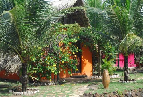 an orange house with palm trees in front of it at Pousada Capitù in Imbassai