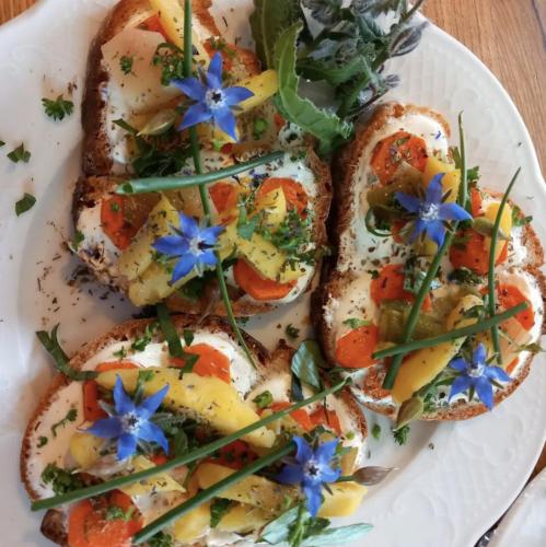 une assiette blanche avec des œufs et des tomates sur du pain grillé avec des fleurs bleues dans l'établissement Maison d'hôtes du Mont, à Morschwiller