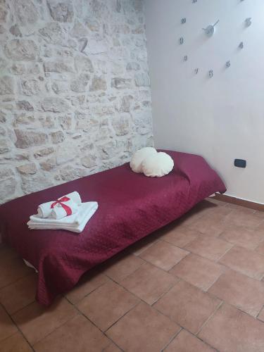 a red bed with two white shoes and a stone wall at La casa nel vico in Molfetta