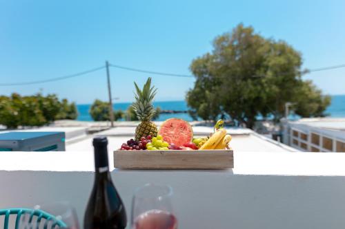 a box of fruit on a table with a bottle of wine at Aegean Gold in Kamari