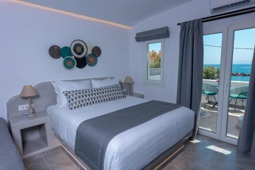 a bedroom with a bed and a balcony with the ocean at Aegean Gold in Kamari
