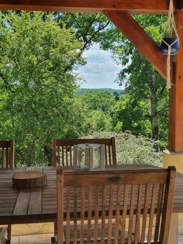 a wooden table and chairs on a deck with trees at Maison Calme au Cœur du Périgord Noir - 3 Chambres in Le Bugue