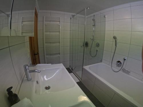 a bathroom with a tub and a shower and a sink at Hinterfoisching - Chalet nahe Kitzbühel in Westendorf