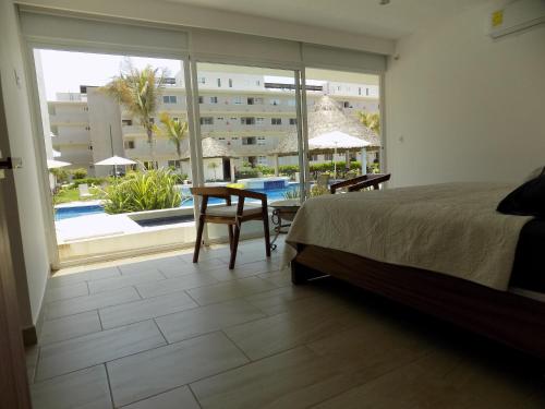 a bedroom with a bed and a table and a large window at Acapulco Diamante Varadero D001 in Acapulco