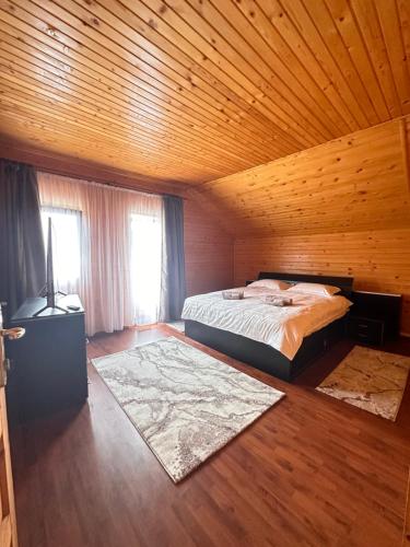 a bedroom with a bed and a wooden ceiling at Ollie's Mountain Chalet in Buşteni