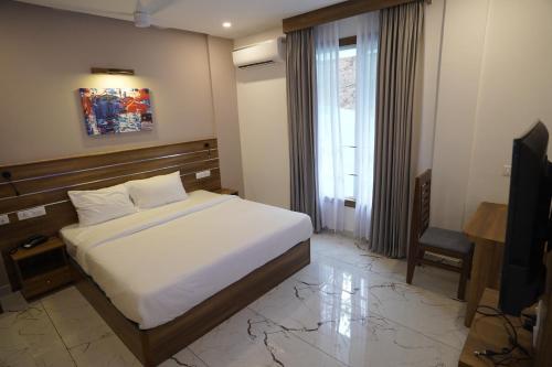 a bedroom with a bed and a window and a television at PUTHUR RESIDENCY HOTELS PVT LTD in Trichūr