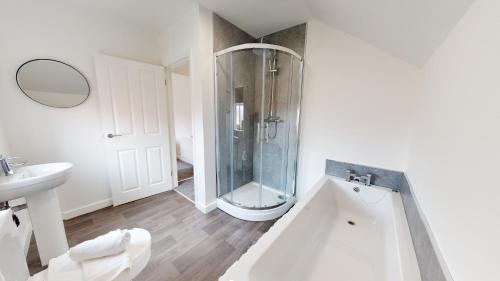 baño blanco con ducha y lavamanos en Stratford House Hartlepool Horizon Stays, en Hartlepool